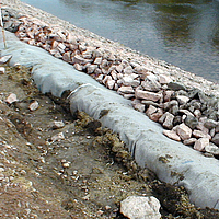 Geotextielvlies en stenen aan de waterkant voor oeverbescherming