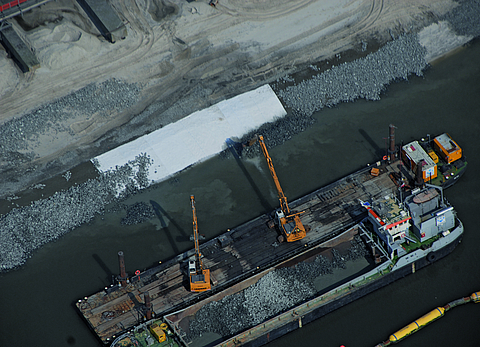 Excavator loading a boat with gravel