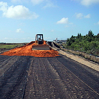 Bulldozer verspreidt zand over een gelegd Basetrac Grid geogrid voor funderingsversterking op een bouwterrein
