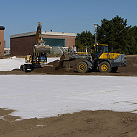 Bulldozer en graafmachine verspreiden grond over gelegde Tektoseal® Clay bentonietmatten