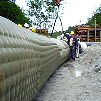 Werknemers vullen de Incomat® Pipeline Cover met betonpomp via de vulopening