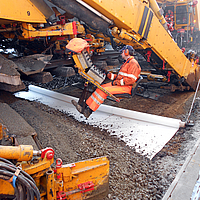 Machine tilt rails op en legt Basetrac® Duo geocomposiet