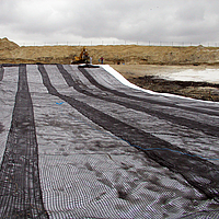 Uitrollen van Basetrac Grid geogrid met een hijsbalk voor versterking van de funderingslaag op een bouwplaats