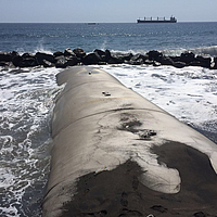 Ingebouwde golfbreker van geotextiel in zee op de achtergrond Waterblokken waartegen de golven slaan