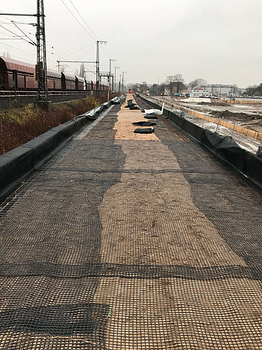 Verlegung von Geogittern neben Schienen als Untergrund der Lärmschutzwand