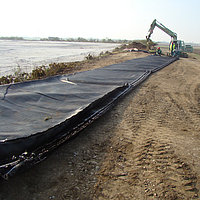 Werknemers werken aan het Basetrac® Woven wapeningsweefsel ter voorbereiding op de installatie