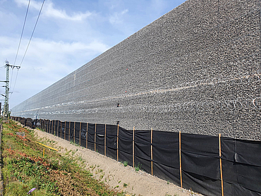 Nahaufnahme der Lärmschutzwand mit Stacheldraht