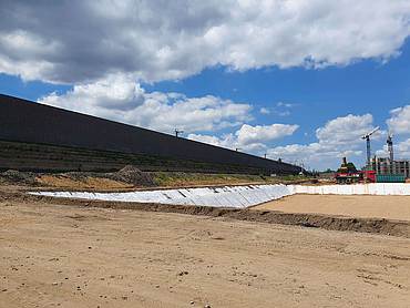 Großbaustelle mit Lärmschutzwand im Hintergrund