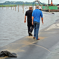 Mensen lopen over een voltooide dam