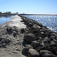 Dam gemaakt van geosynthetics, bekleed met stenen en zand